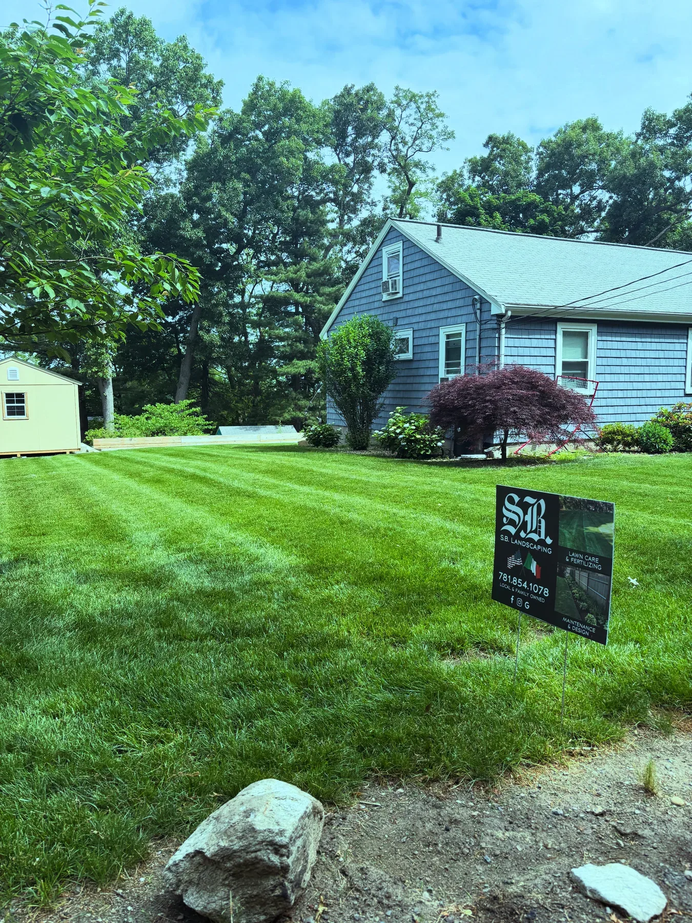 Freshly maintained residential lawn with S.B. Landscaping yard sign