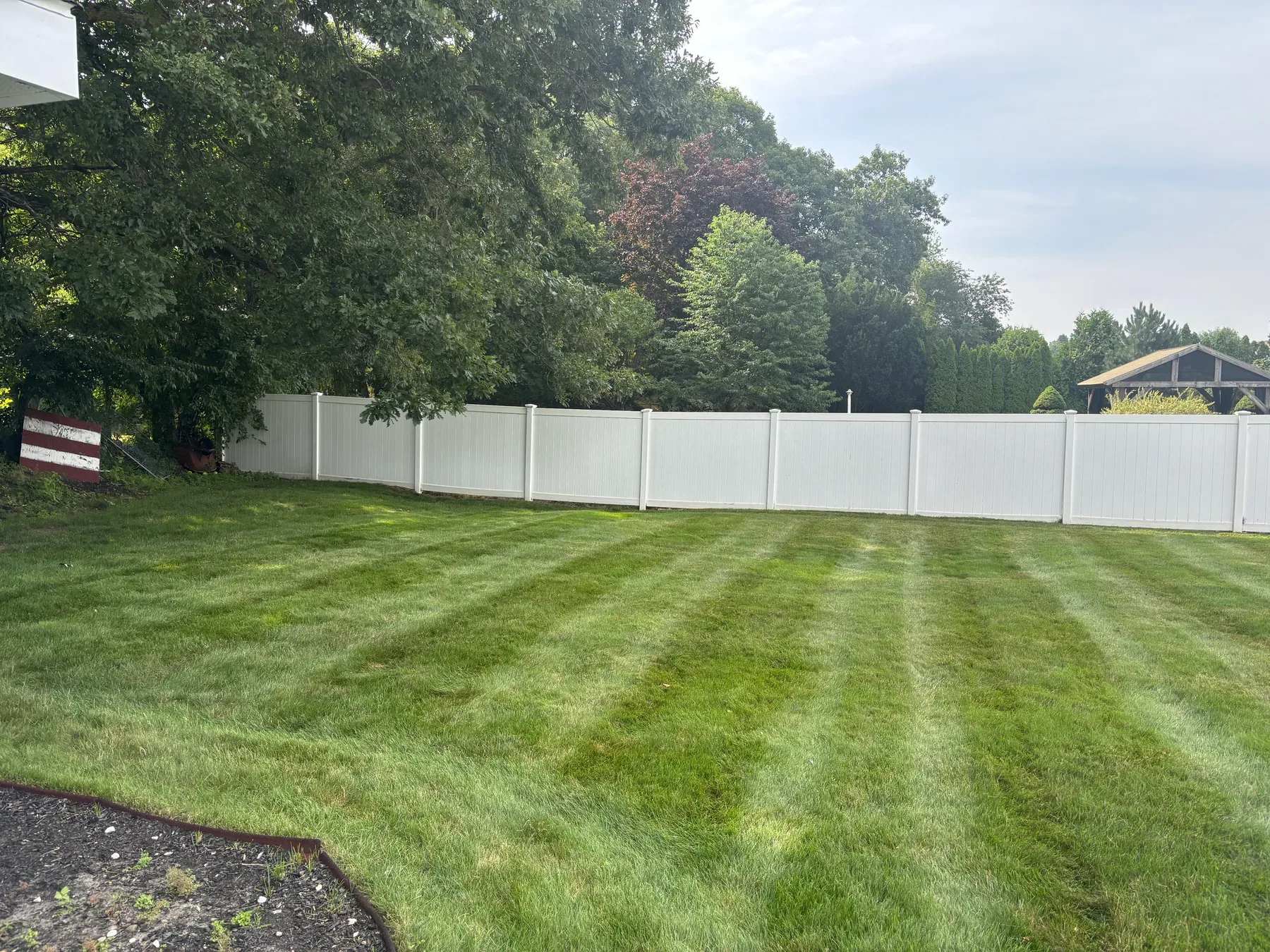 Striped backyard lawn after maintenance by S.B. Landscaping