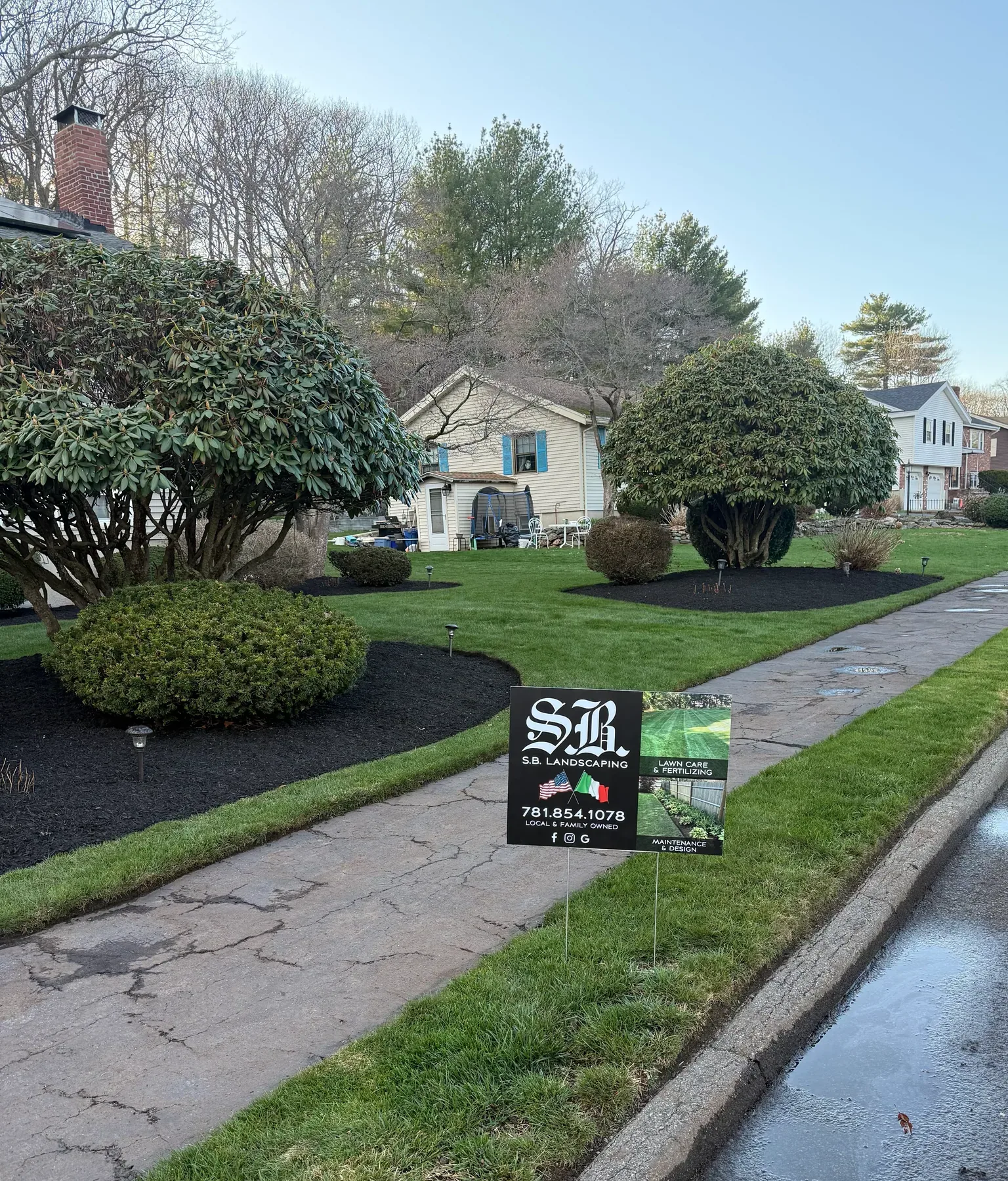 Fresh mulch beds and maintained shrubs with S.B. Landscaping yard sign
